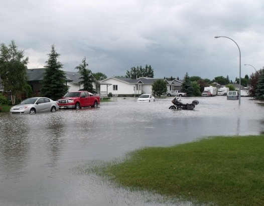 Flooded Neighborhood with Waters Completely Covering Streets and Surrounding Lawns