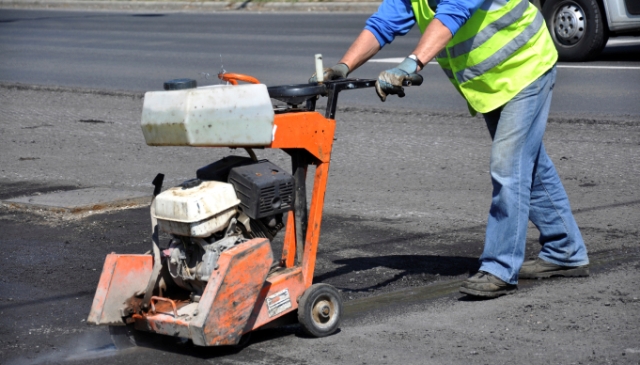 Road Worker Running Machinery Around a Pothole