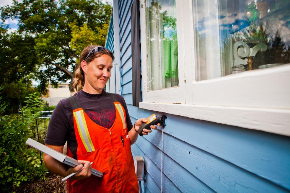 Utility Worker Checking a Meter Behind a House